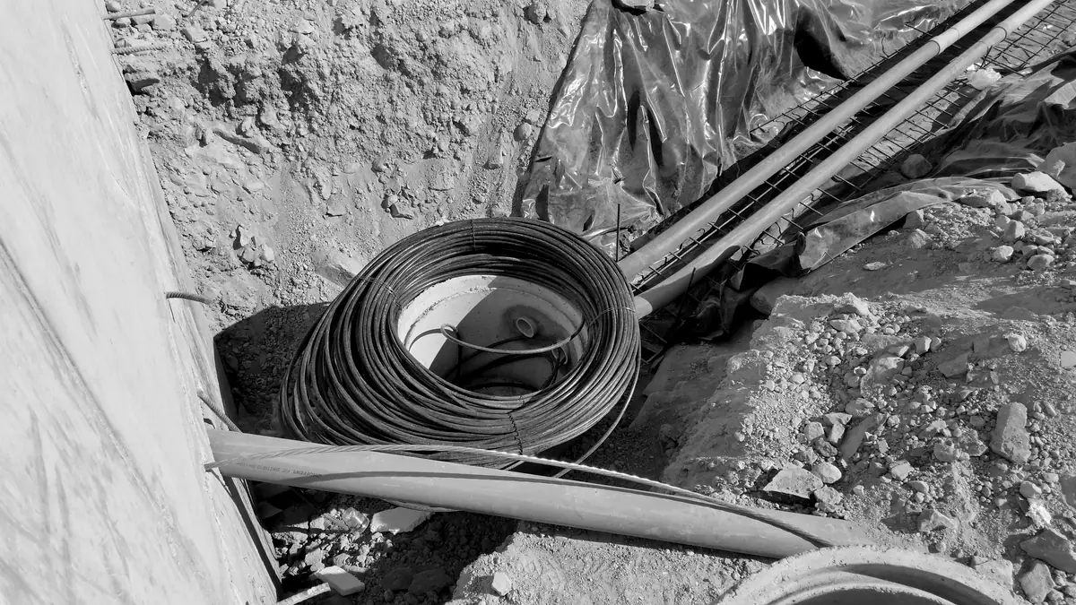 Coiled telecommunications cable and conduit laid in an open trench